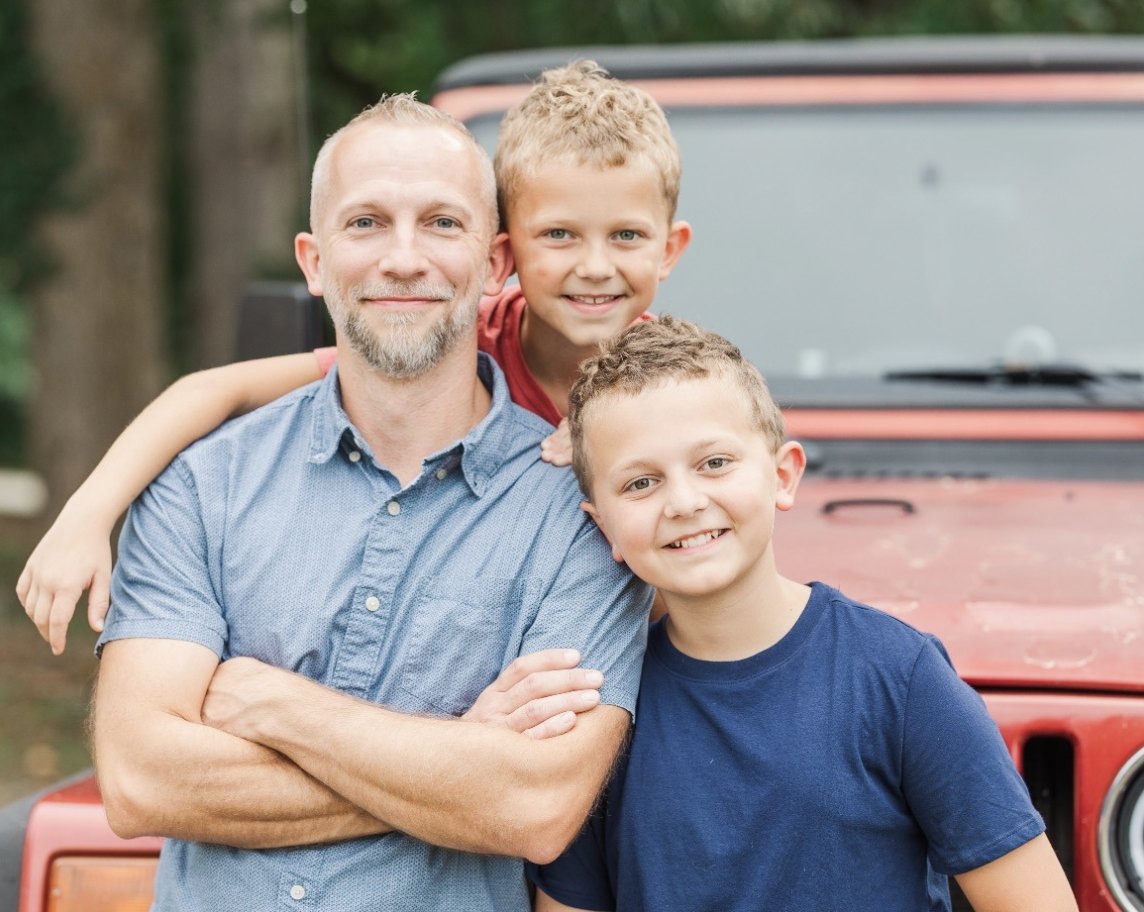 Clint with his boys in front of a red Jeep